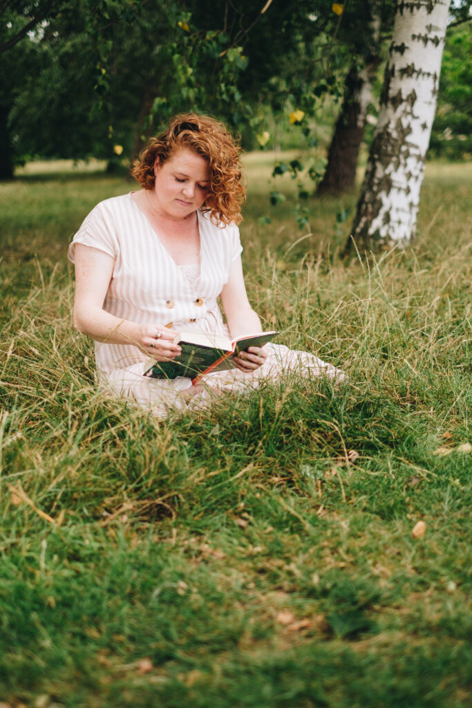 Jo Hooper, rebellious business coach at Get Wildly Free is sitting in the grass reading