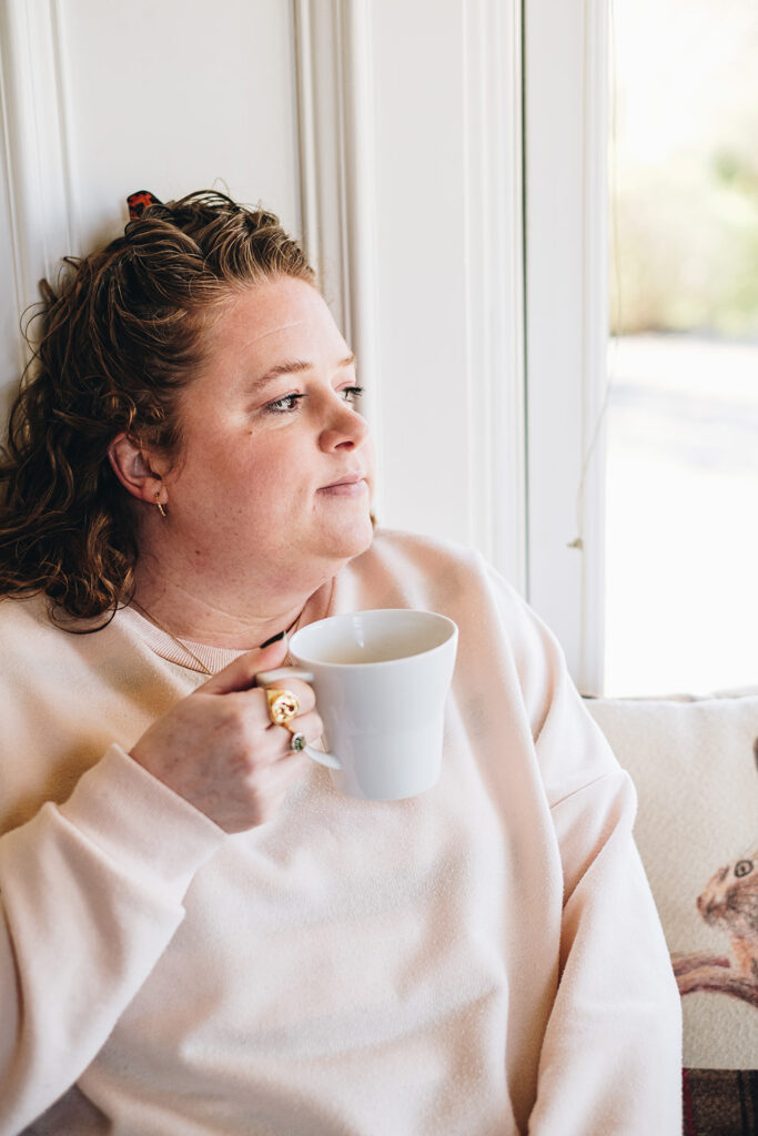 Jo Hooper, rebellious business coach at Get Wildly Free sits by a window drinking tea