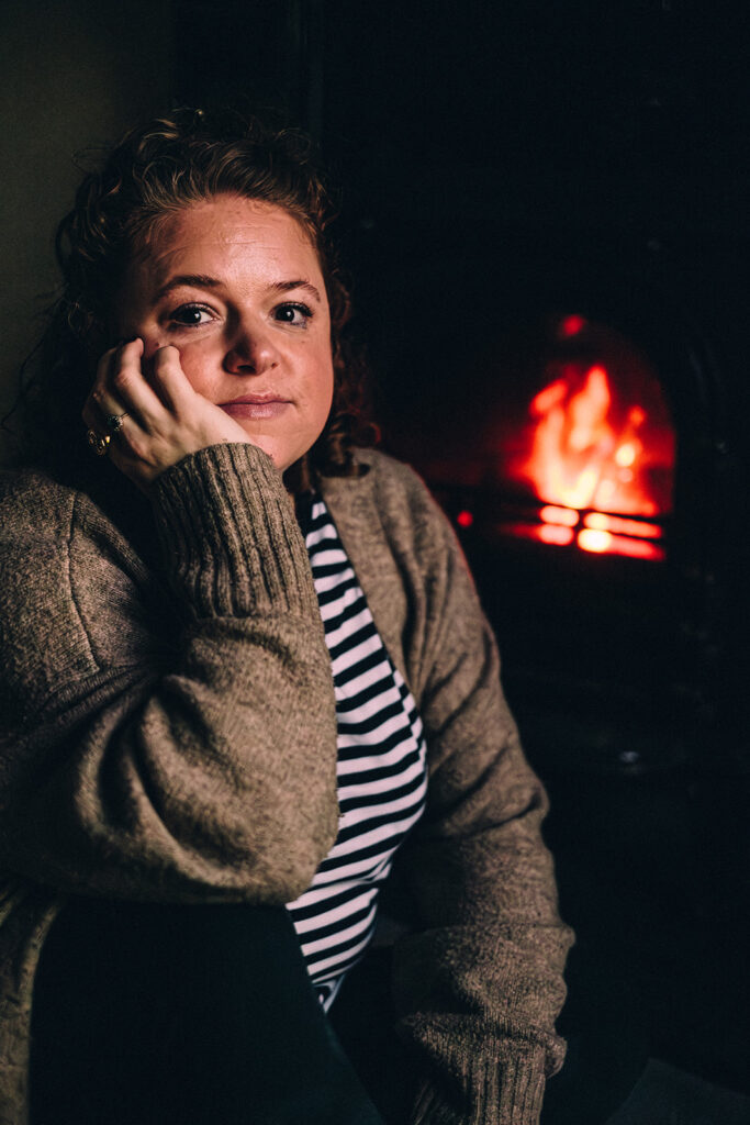 Jo Hooper, rebellious business coach at Get Wildly Free sits in front of a fire