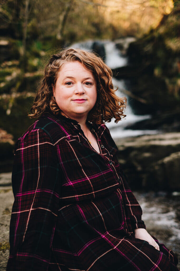 Rebellious business coach, Jo Hooper sits next to a waterfall