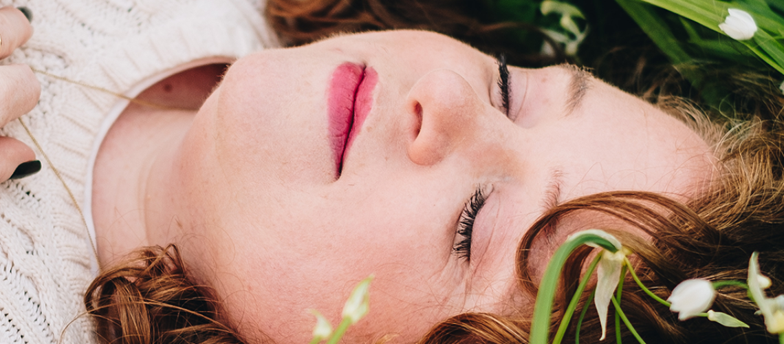 Jo Hooper, Business Coach in Wales, UK is lying in grass with her eyes closed